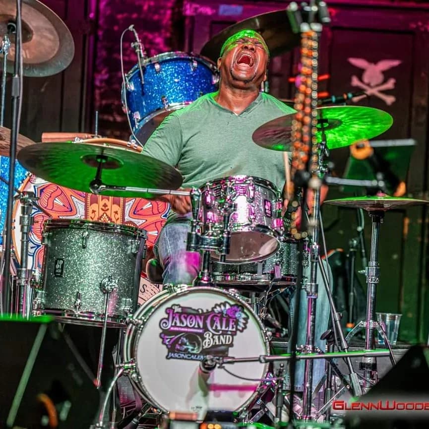 Ed Williams behind the kit, teal-lit